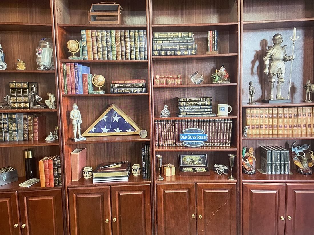 Bob’s home office bookshelves with leather-bound books, knights, and his father’s flag